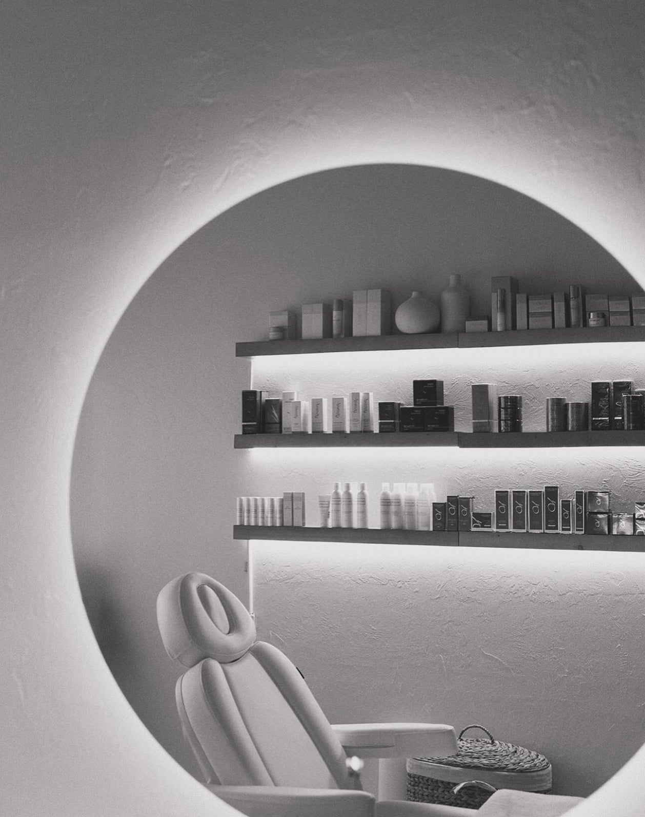 Modern interior with a round alcove containing a chair and shelves with decorative items.